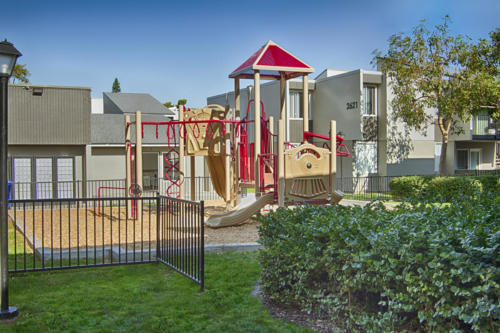 An apartment complex with a playground in the front yard.