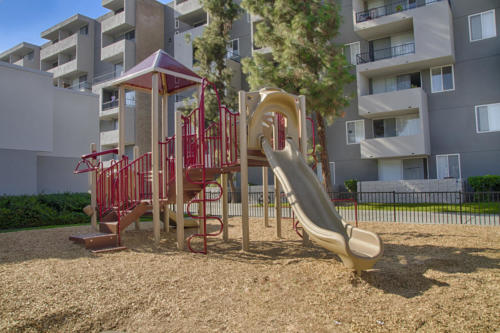 A playground with a slide in front of apartment buildings.