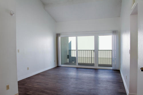 An empty room with hardwood floors and sliding glass doors.